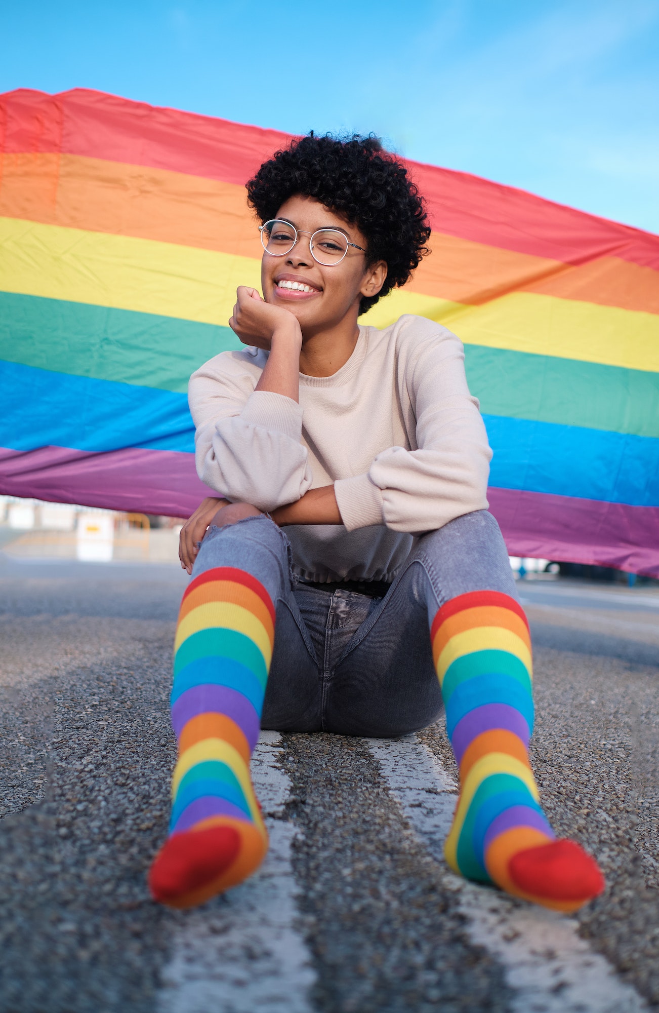 African American woman ooking at the camera wearing lgbt rainbow socks as well as a flag